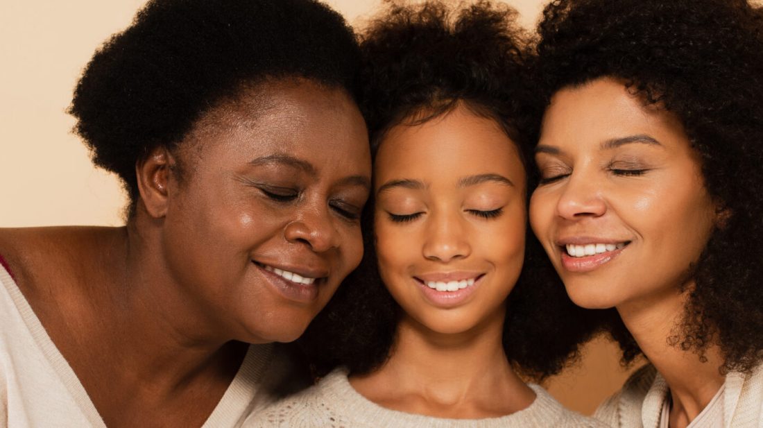 african american daughter, granddaughter and grandmother hugging cheeks to cheeks on beige background, banner